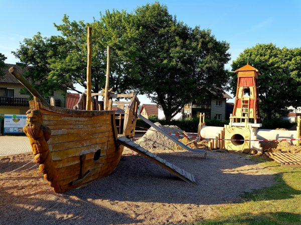 15.06.2022: Es geht weiter. Heute brauchte es Großgerät. Für die Betonfertigteile und den Leuchtturm rückte ein Autokran an. Mit 6m Höhe ist er schon ziemlich hoch. Kletternetz, Kletterwand und Riesenrutsche werden in ein paar Wochen die Kinder erfreuen. Für die drei Tunneleingänge suchen wir noch Namen, z.B. Schatzhöhle, Piratentunnel. Wer hier eine Idee hat, einfach Kommentar mit Namensvorschlag schreiben.