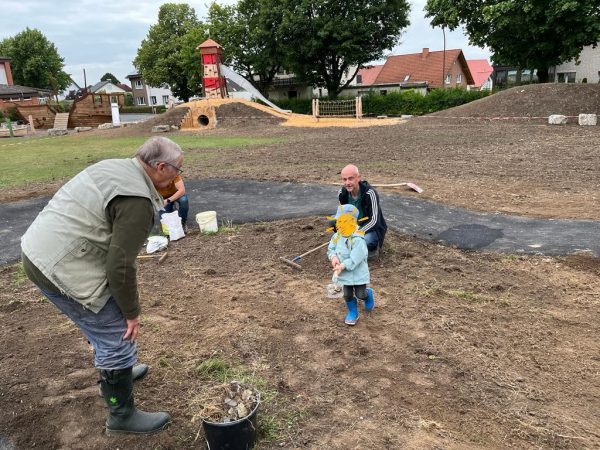 11.07.2022: Heute wurde die Fläche für die Blühwiese in der Mitte der Asphaltbahn vorbereitet: Geharkt, Steine aufgesammelt und eingesät. Bald blühen hier Wildblumen für Hummeln, Bienen, Schmetterlinge & Co. Im Hintergrund wächst bereits ganz leicht der neue Rasen. In der nächsten Woche werden Tore, Ballfangzaun und Tischtennisplatte wieder aufgestellt.